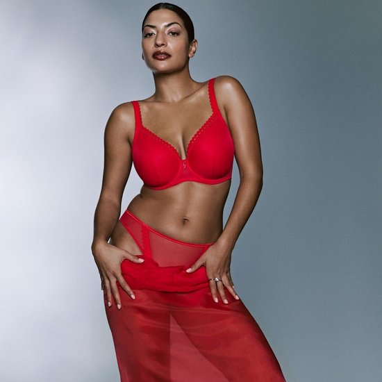 Model in rode beugelbh met kanten randje, slip en doorschijnende rok.