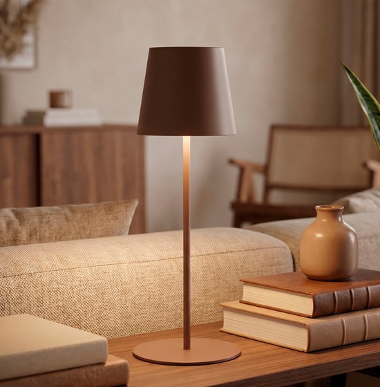Lampe de table marron sur une table en bois dans un salon, avec des livres et un vase.