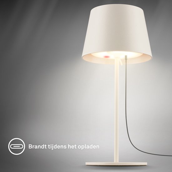 Une lampe de table blanc cassé allumée pendant la charge via un câble noir.