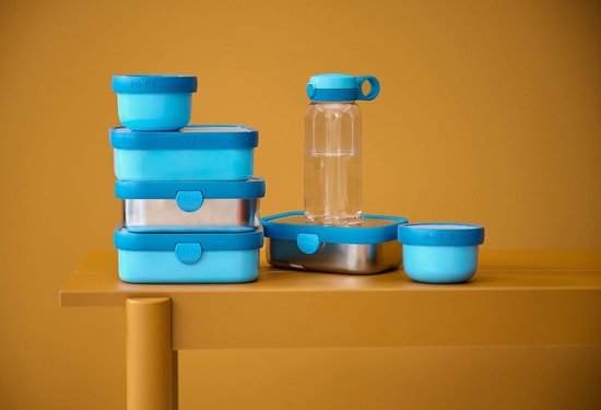 Blauwe Mepal lunchboxen en fles met water gestapeld op een tafel.