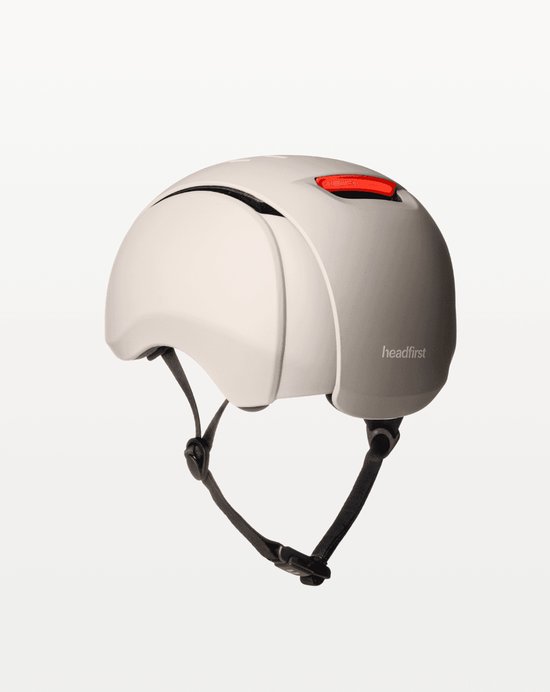 Beige Headfirst fietshelm, zijaanzicht, met rode reflector en verstelbare bandjes.