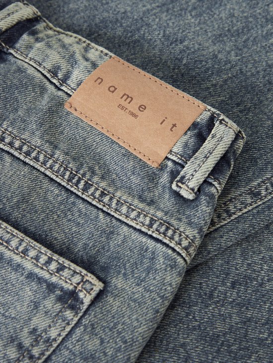 Lichtblauwe wijde jeans met bruin leren 'name it' label en 'EST. 1986' op de achterkant.