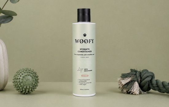 Lichtgroene fles met zwarte dop voor hondenshampoo. "WOOFY HYDRATE CONDITIONER FOR ALL AGES DOGS" met "COCONUT" label.