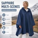Vrouw in marineblauwe regenponcho, met bergen op de achtergrond. Poncho geschikt voor regen, klimmen, wandelen, casual en straat.