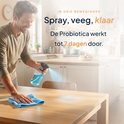 Man spuit op een houten tafel en veegt met een doek. Tekst: Spray, veeg, klaar.