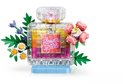 Flacon de parfum transparent avec couches jaunes, oranges et roses, étiquette 'Flower Spark', fleurs roses et petites fleurs violettes.