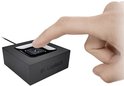 Een hand drukt op het blauw verlichte Bluetooth-logo van een zwarte Logitech adapter.