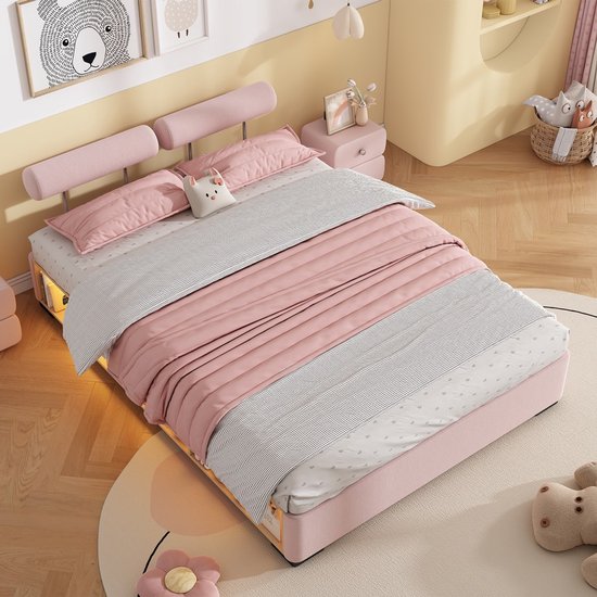 Roze kinderbed opgemaakt met roze en grijs beddengoed, twee roze hoofdkussens en een knuffel.