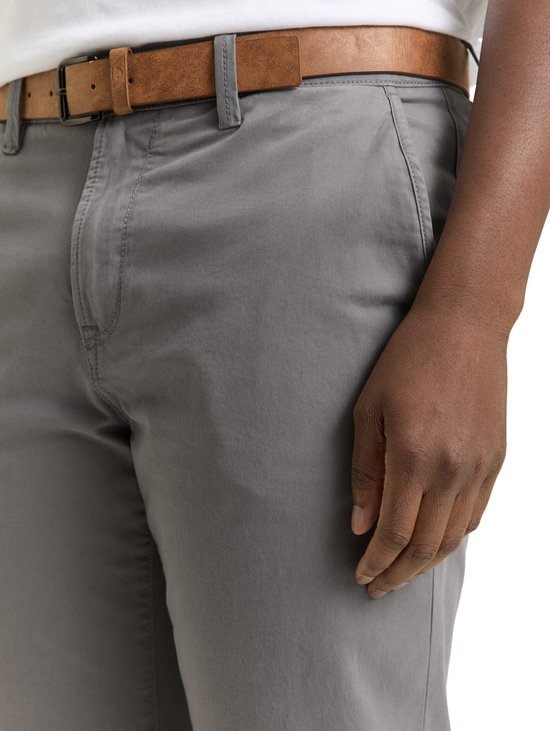 Grijze chino broek met bruine riem, detail van de heup en zak.