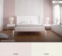 Een wit bed met grijze lakens en gele lampen staat in een slaapkamer met een roze en creme gestreepte muur en verticaal bloesemdessin.