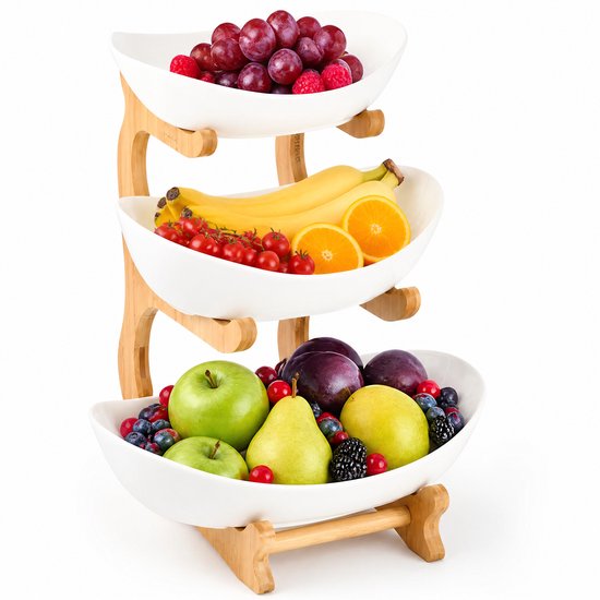 Drielaagse fruitschaal met witte kommen en naturel bamboe standaard, gevuld met diverse soorten fruit.
