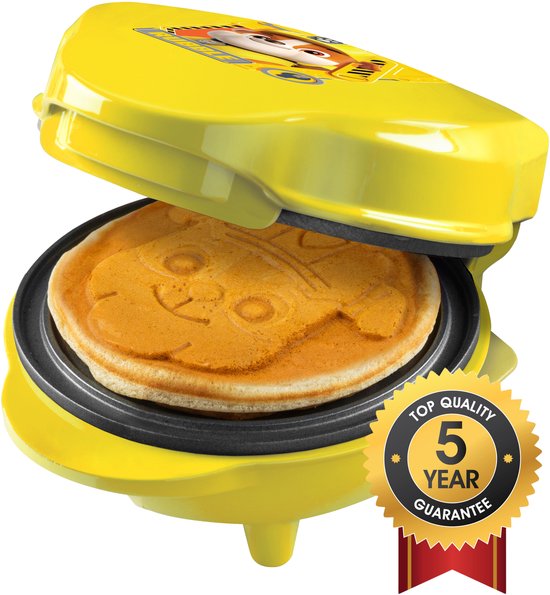 Geel wafelijzer met open deksel waarop een wafel met de afbeelding van Rubble uit Paw Patrol is gebakken. Een gouden zegel met "5 YEAR GUARANTEE" is zichtbaar.