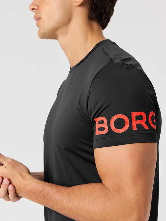 Close-up van een man in zwart sportshirt, met rode Björn Borg letters op de mouw.