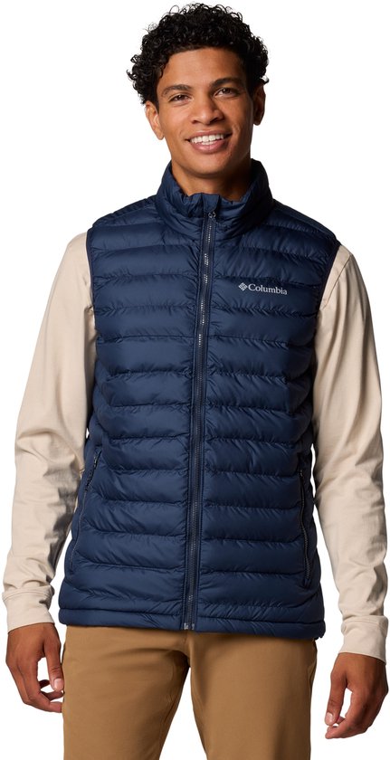 Blauwe Columbia bodywarmer met rits, gedragen door een man met beige shirt en bruine broek.
