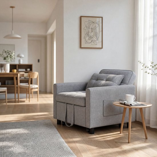 Grijze fauteuil met opbergvakken aan de zijkant en een uitklapbaar voetenbankje.
