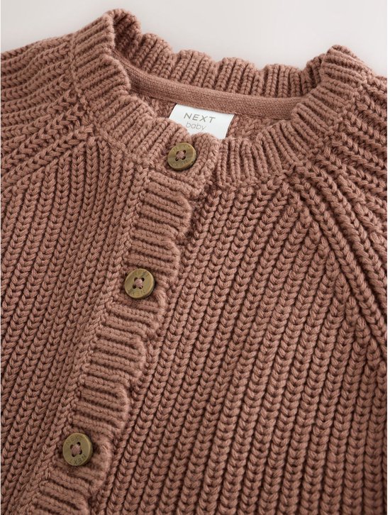 Close-up van de bruine gebreide babyvest met knopen en kraag.