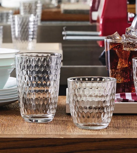 Deux verres à motif nid d'abeille, un grand et un petit, sur une table en bois.