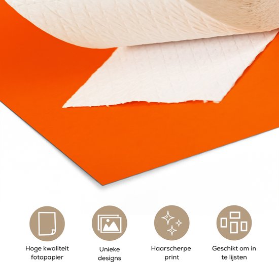 Close-up van een wc-rol met scheurende stukken papier op oranje achtergrond.