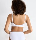Achterkant van een witte Sloggi beha zonder pads, gedragen door een vrouw met krullend haar.