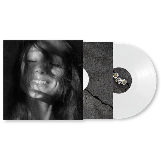 Disque vinyle blanc avec pochette présentant une photo noir et blanc d'une jeune fille souriante et un gros plan sur de la pierre fissurée avec des marges.