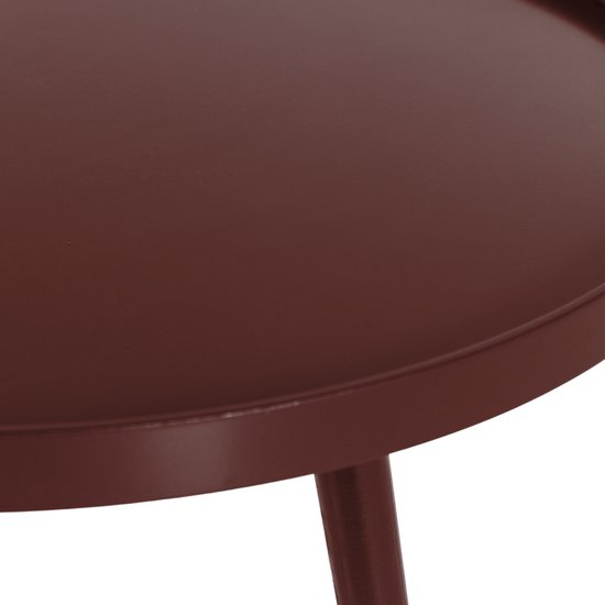 Close-up van de bordeauxrode rand van een ronde bijzettafel met een poot.