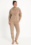 Bruin fluwelen joggingpak met capuchon en trekkoord, gedragen door een model.