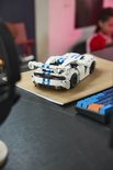 Witte LEGO Technic Dodge Viper GTS-R sportauto met blauwe strepen staat op een bureau, naast een toetsenbord.