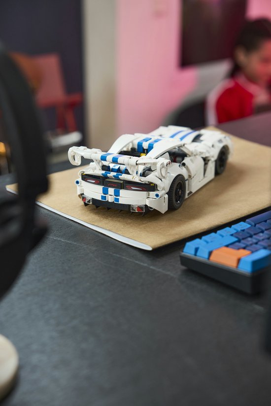 Witte LEGO Technic Dodge Viper GTS-R sportauto met blauwe strepen staat op een bureau, naast een toetsenbord.