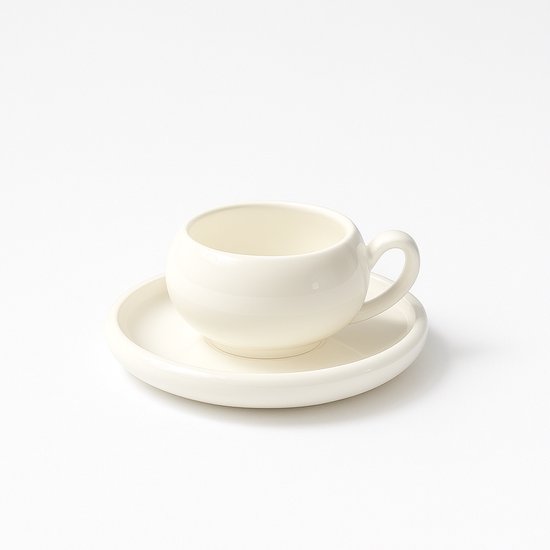 Une tasse à expresso ronde et blanche avec une soucoupe, sur fond blanc.