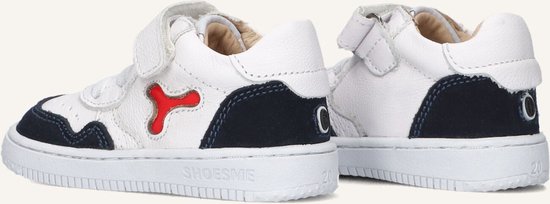 Twee witte leren sneakers met donkerblauwe suède accenten. Veters, klittenband en rode details. Nummer 21 op zool.