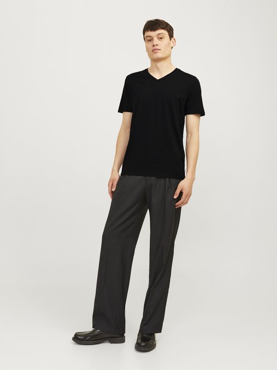 Man met zwarte T-shirt met V-hals en lange grijze broek.