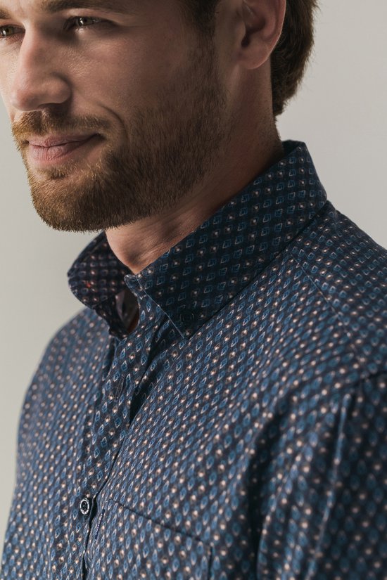 Close-up van de button-down kraag en het geometrische patroon van het donkerblauwe overhemd.