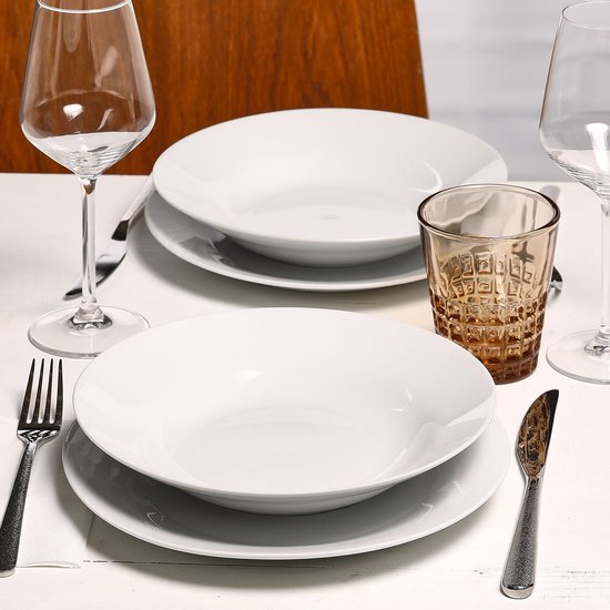 Tafel gedekt met witte borden, glazen en bestek.