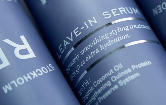 Close-up van blauwe REF Stockholm flessen met tekst "Leave-in Serum".