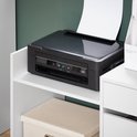 Zwarte printer op een witte legplank van een bureaukast. Opbergdoos eronder.