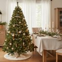Gedecoreerde kunstkerstboom met gouden ornamenten en warme LED-lampjes, naast een gedekte eettafel.