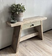 Houten bankje met een lade met groen front en zwarte knop. Decoratie: plant in grijze pot, groene kandelaar.