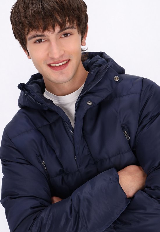 Close-up van een man in een donkerblauwe MO parka met capuchon. Ritsen en stoffen details zichtbaar.