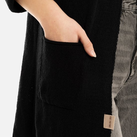 Detailopname van een zwarte gebreide zak op een lang vest.