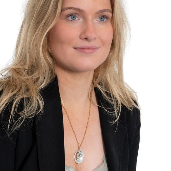 Model met blond haar draagt een gouden ketting met een ovale hanger.