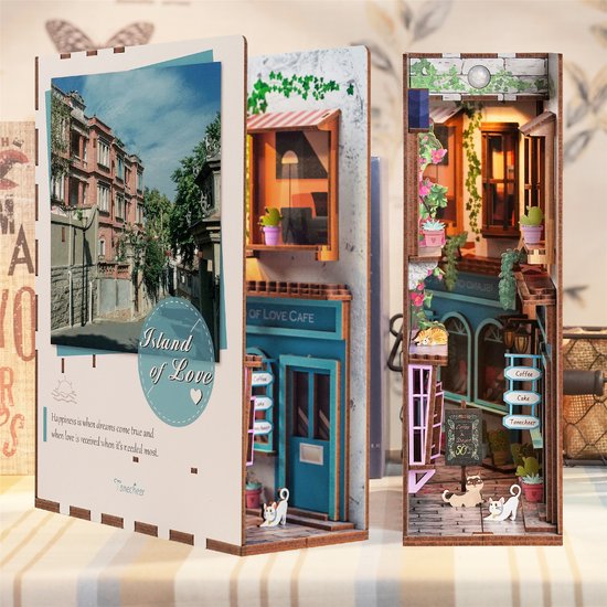 Boekensteun 'Island of Love' tentoongesteld tussen boeken, met gedetailleerde café-gevel en stadsafbeelding.