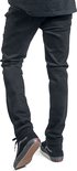 Achterkant van de benen van een man in zwarte skinny jeans en zwarte hoge Vans sneakers.