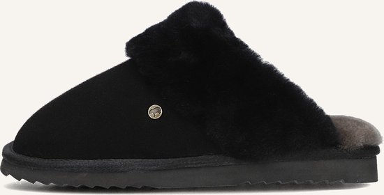 Zijzicht van een zwarte suède slof met dikke zwarte schapenvacht en een goudkleurig logo.