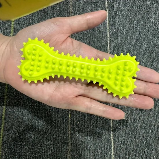 Hand die een geel botvormig kauwspeeltje vasthoudt, met nopjes.