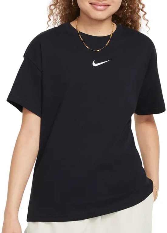 Model met een zwart Nike T-shirt met klein wit logo op de borst, gedragen met beige broek.