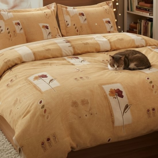 Gele dekbedovertrek met bloemenprint, twee kussenslopen. Kat slaapt op het bed. Dichtbij opname.