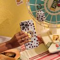 Lichtblauwe telefoonhoes met bruine stippen en beige bloemen, met een ringhouder op de achterkant.