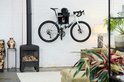 Witte racefiets met een Stasdock muurbeugel, opgehangen aan een witte bakstenen muur.
