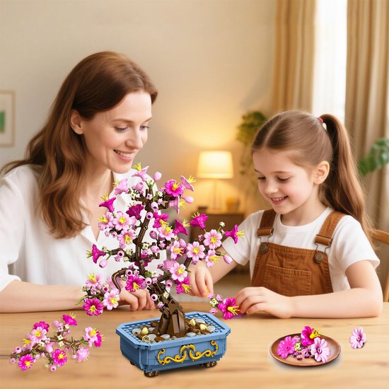 Mère et fille construisant un bonsaï de fleurs de cerisier roses dans un pot bleu.
