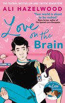 Boekcover van 'Love on the Brain' van Ali Hazelwood. Een man met zwart haar draagt een vrouw die hem bij zijn stropdas trekt. Roze en blauwe illustratie.